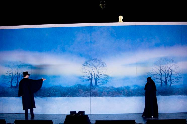EUGEN ONEGIN, Bühnenbild Alissa Kolbusch. Eine lange Wand mit einer Schneelandschaft als Tapete. Davor stehen 2 Herren in schwarzen Mänteln zum Duell.