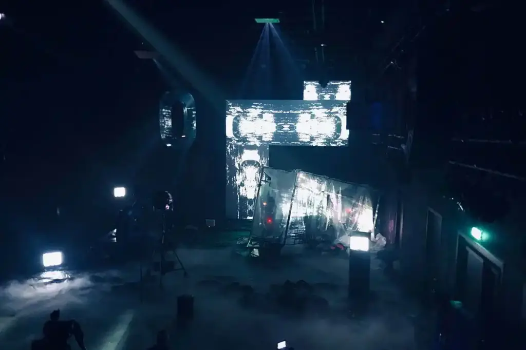 GROUND CONTROL Maxim Gorki Theater Berlin, Bühne: Alissa Kolbusch. Hinten rechts ein halb versunkener Glaskasten, auf dem Boden und im Hintergrund eine Videoinstallation in weißem Licht.